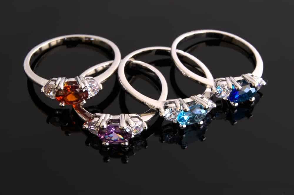 Various birthstone rings on a dark surface.