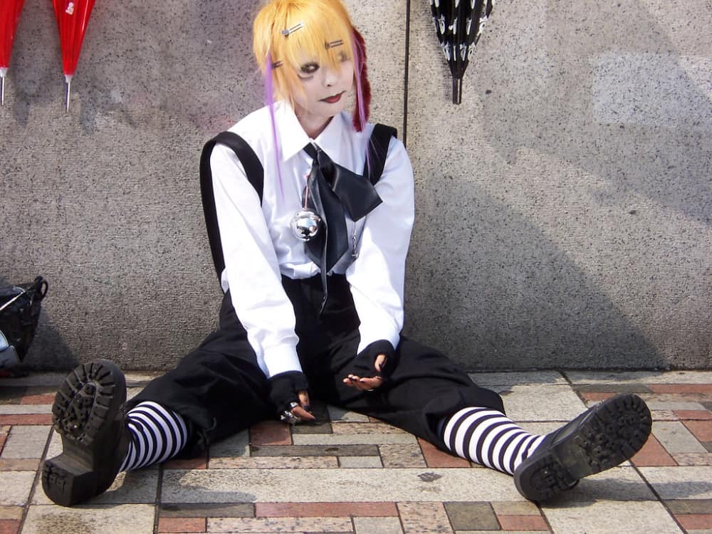 Man in kodona outfit sits on the street.