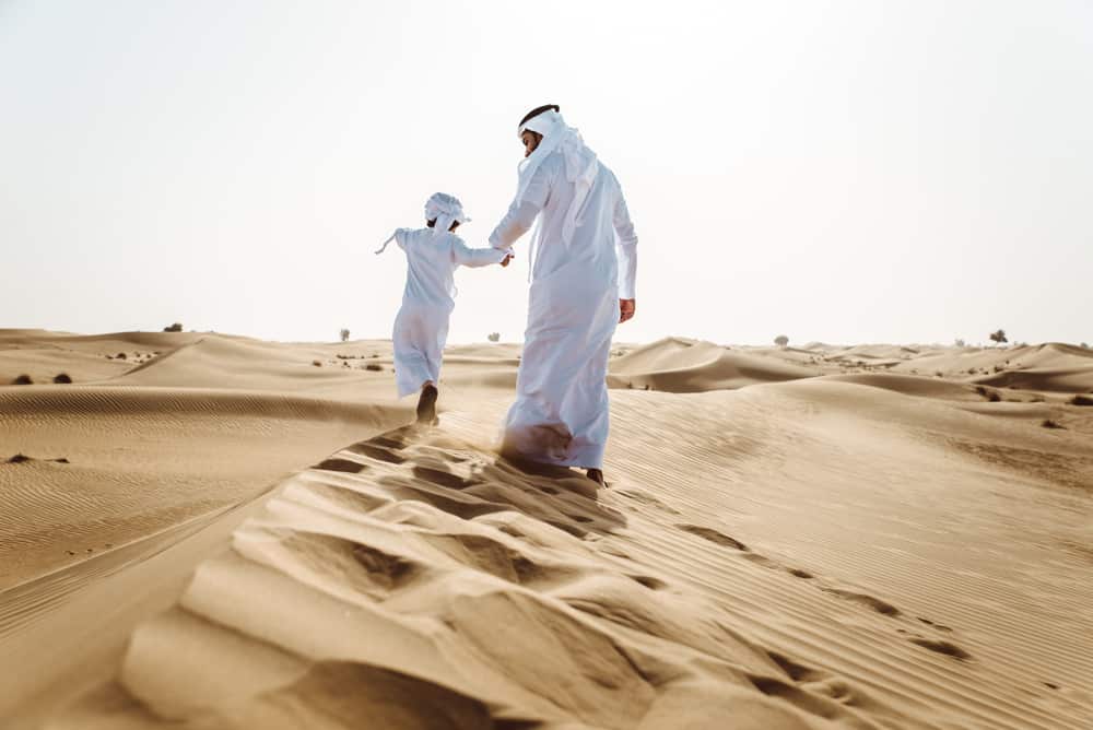 Un homme arabe avec son fils dans le désert.