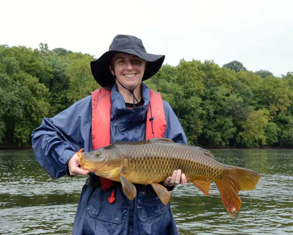 A woman wearing rain gear displaying her catch.