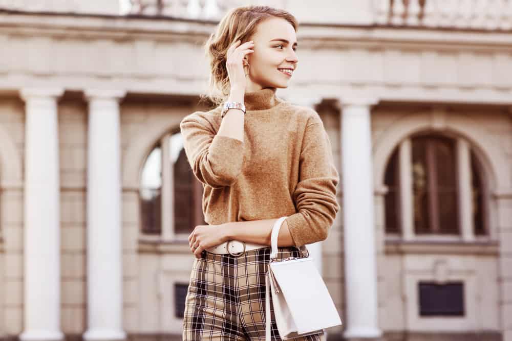 This is a close look at a woman wearing a brown cashmere sweater outside.