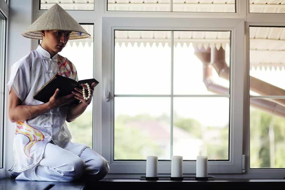 A monk wearing a straw conical hat and a white traditional garb.