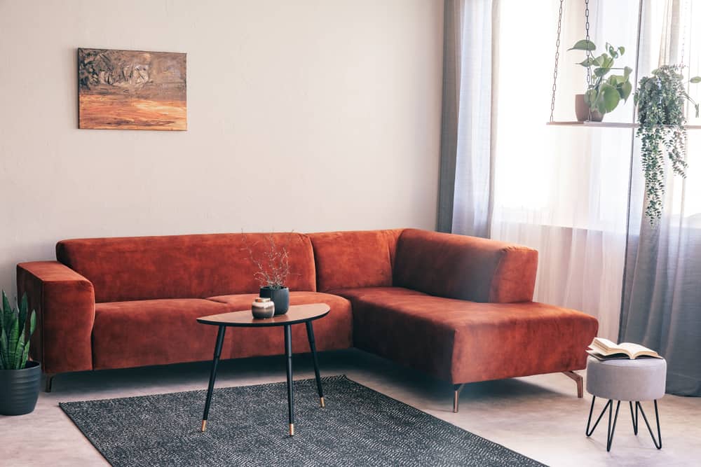 This is a living room with a reddish brown suede sectional sofa.