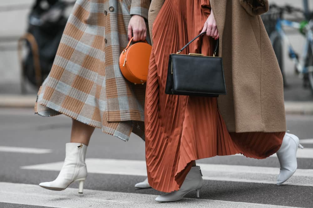 A close look at stylish women crossing the street wearing skirts and heels.