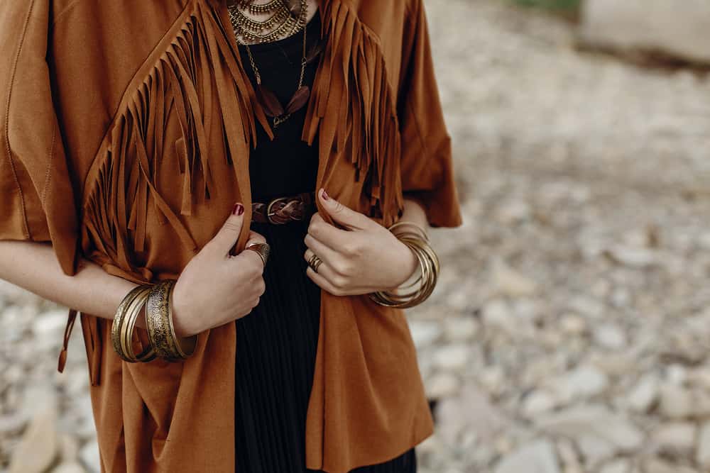 A woman wearing a brown fringe suede jacket.