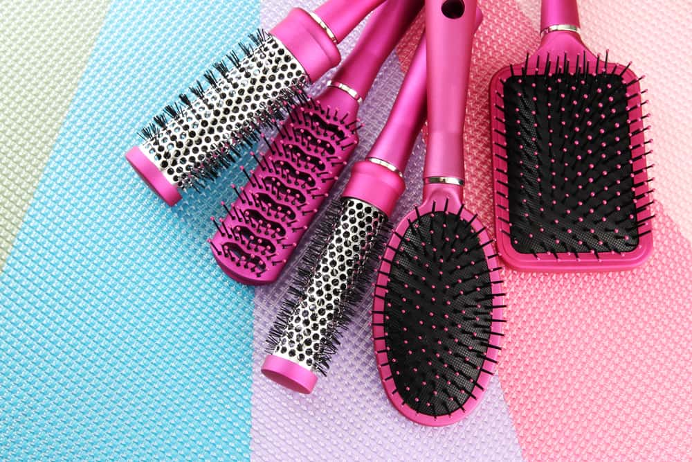 These are various hair brushes on a colorful surface.