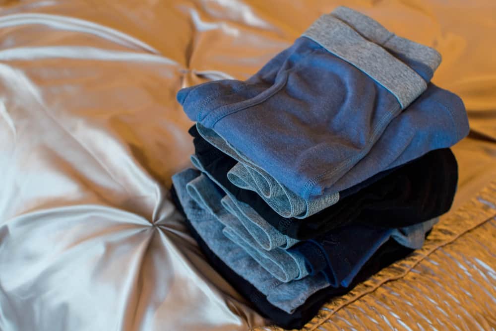 Men's folded cotton underwear piled on the bed.