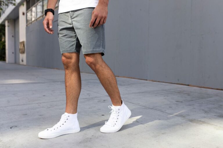 Man wearing gray shorts and whote sneakers.