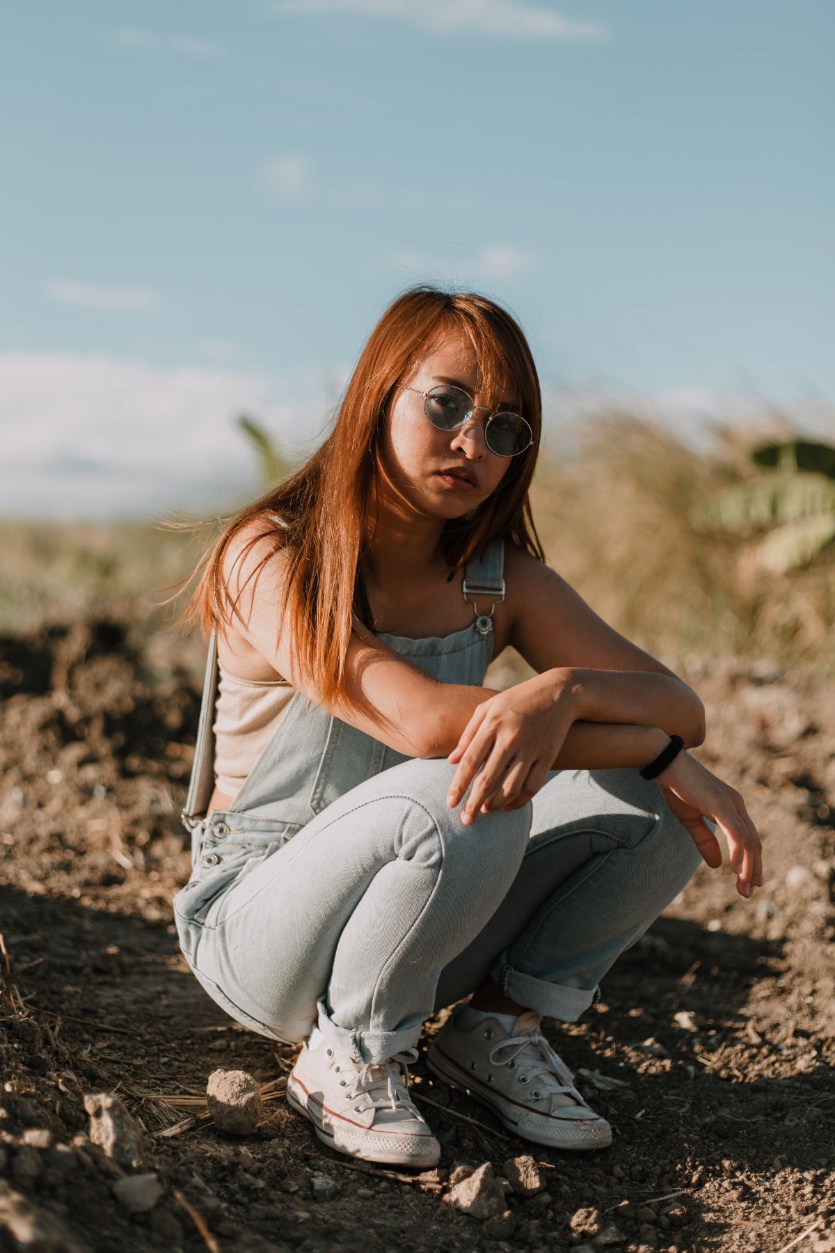 Sitting down looking at camera wearing overalls