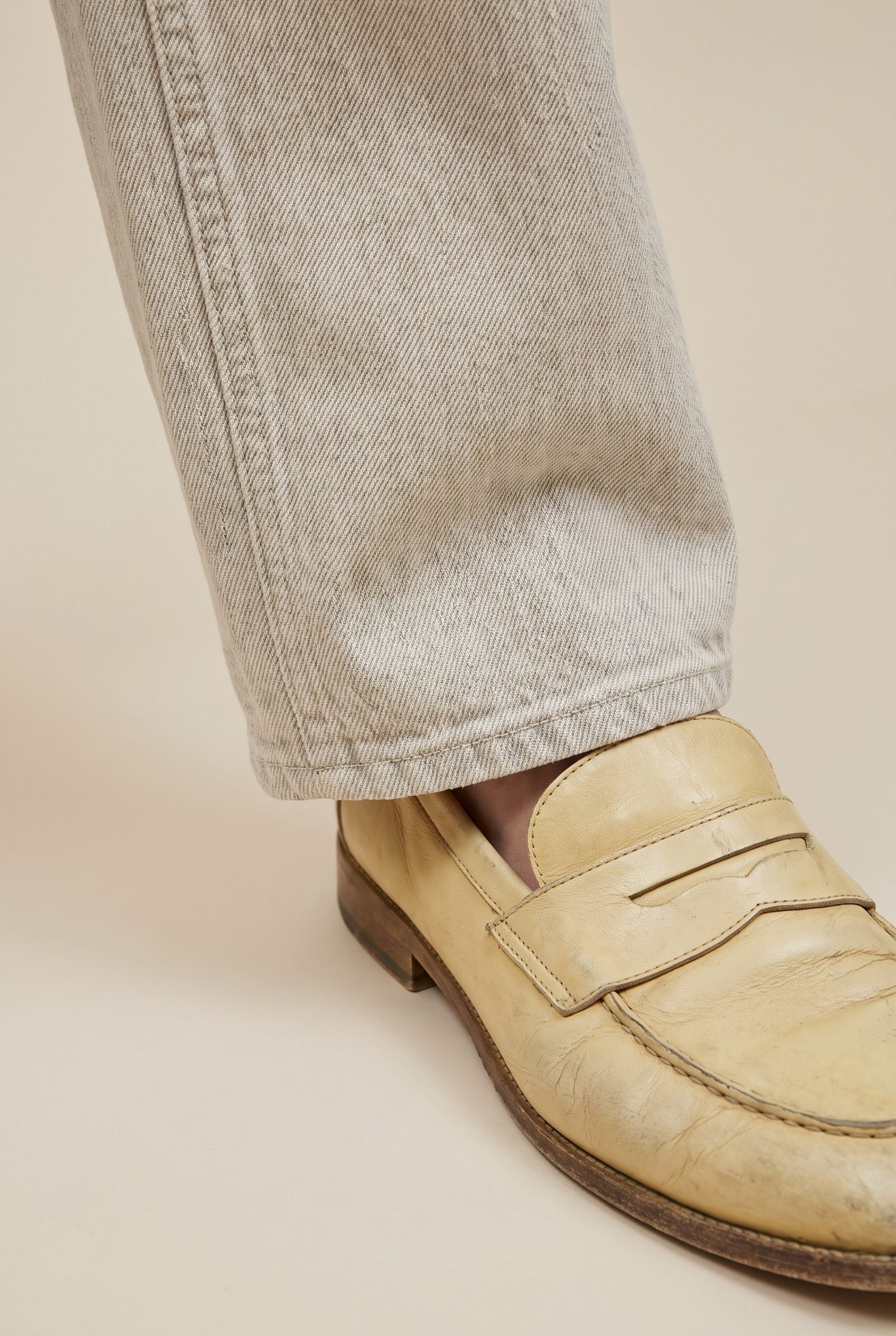 Woman in fresh ecru jeans and yellowed cream loafers, the two off-whites failing to match.