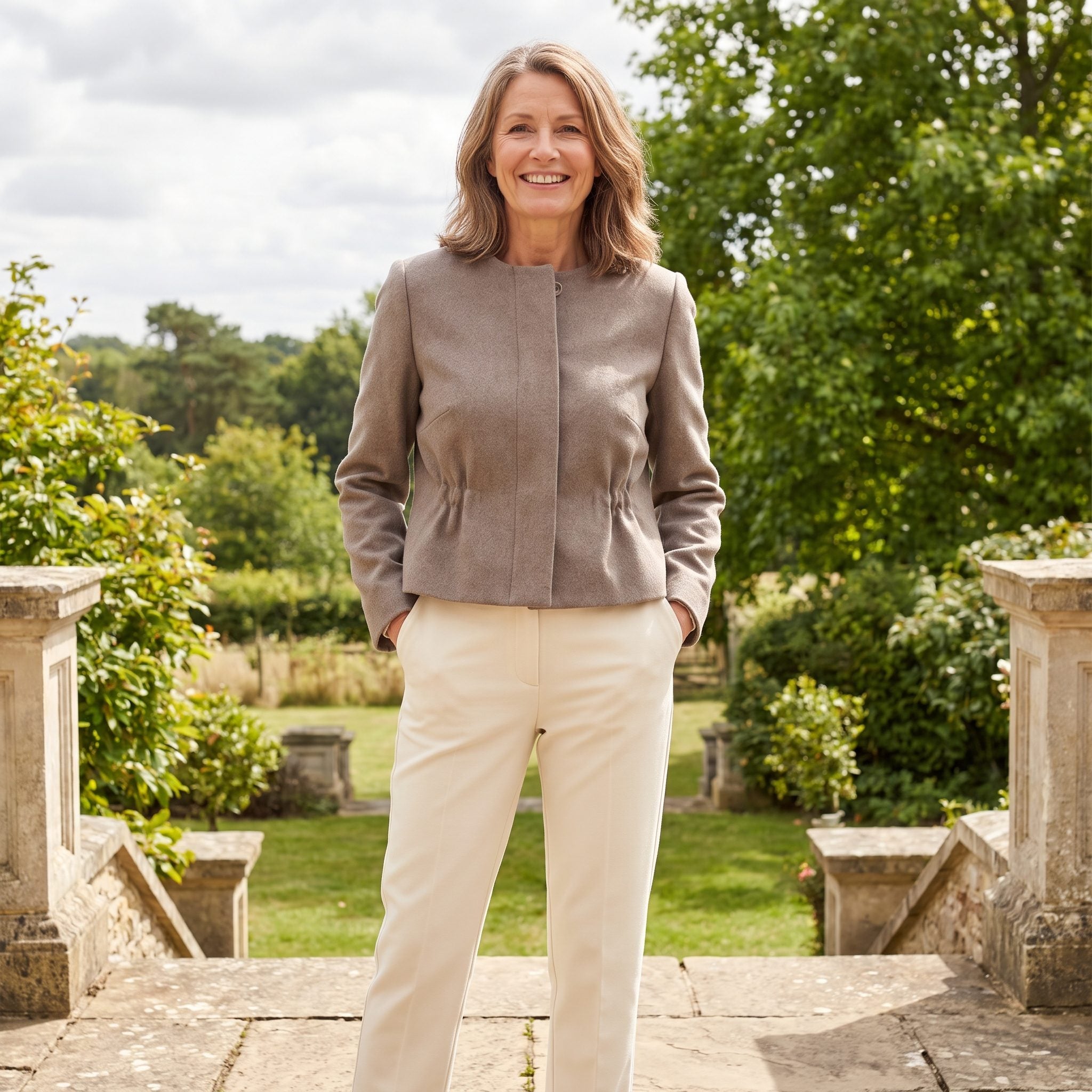 Woman in a softly shaped grey cropped jacket with subtle waist shaping over straight-leg charcoal trousers.