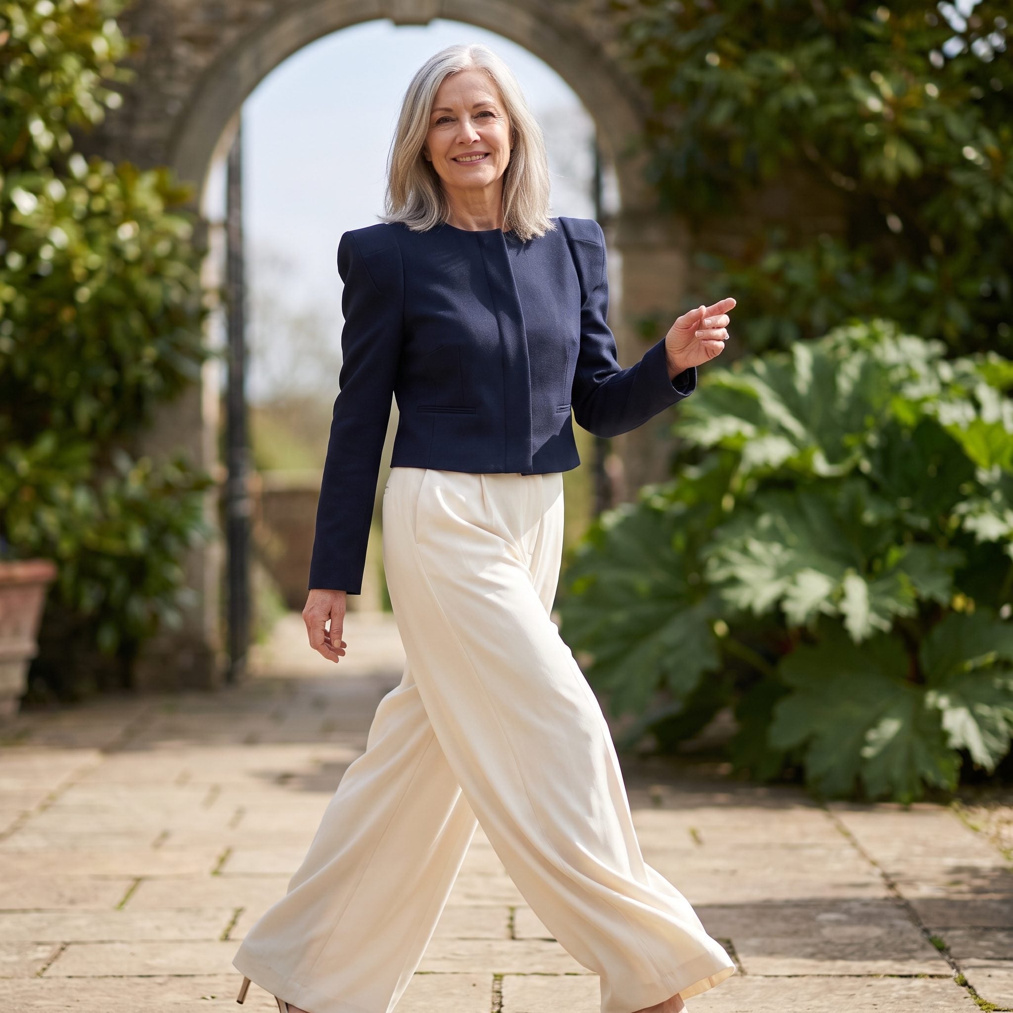 Woman in a structured navy cropped jacket and high-waisted charcoal wide-leg trousers with pointed heels.