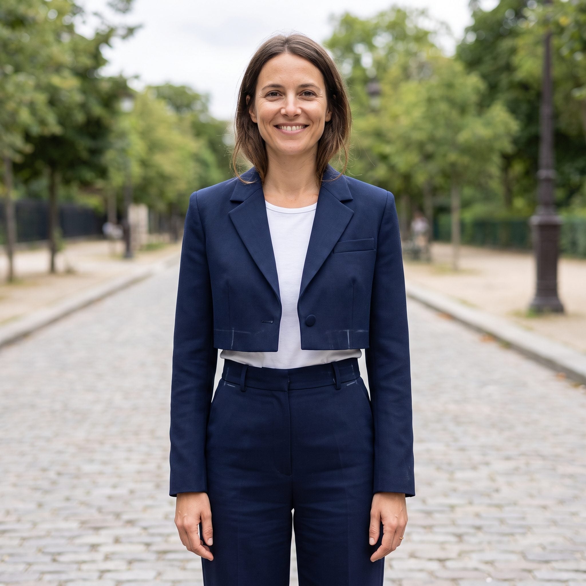 Woman in a black cropped jacket ending above the waist over a fitted top and slate mid-rise trousers.