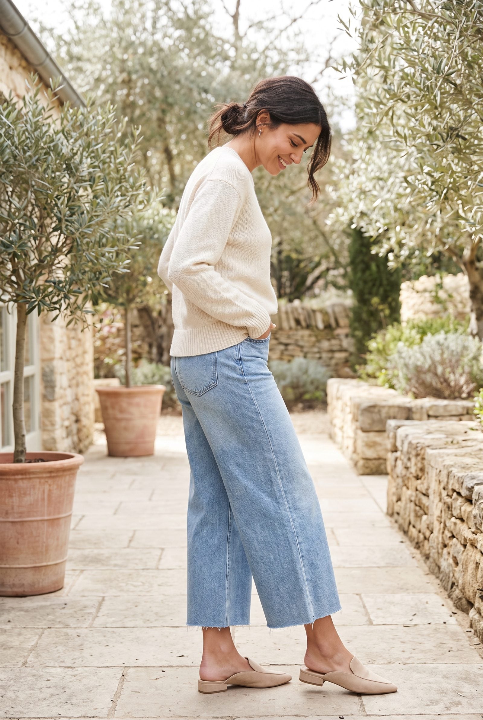 Woman in wide-leg cropped jeans and small backless loafer mules with a wide gap of bare ankle showing.