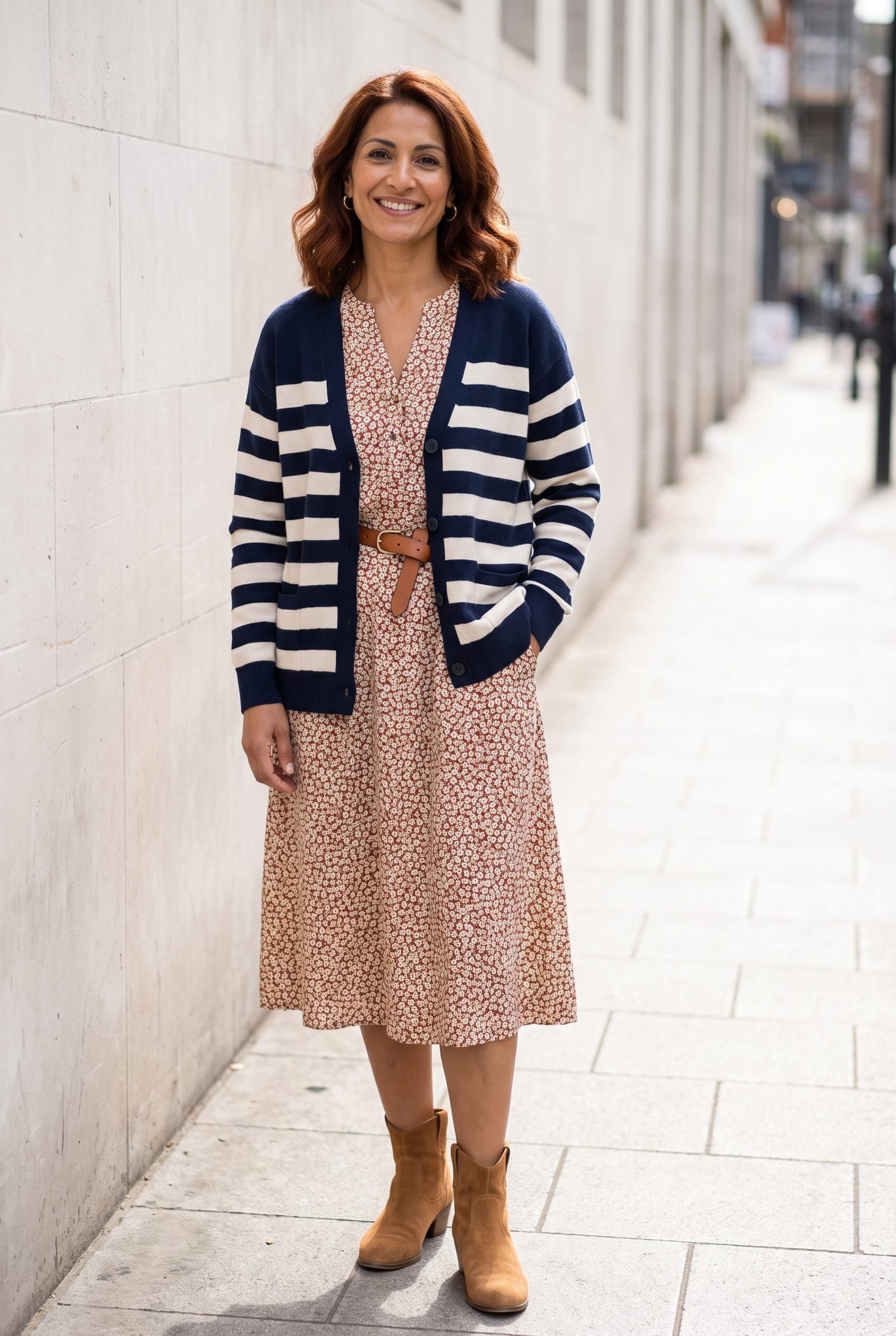 Woman in a small-print floral tea dress under a wide navy-and-cream horizontal striped cardigan.