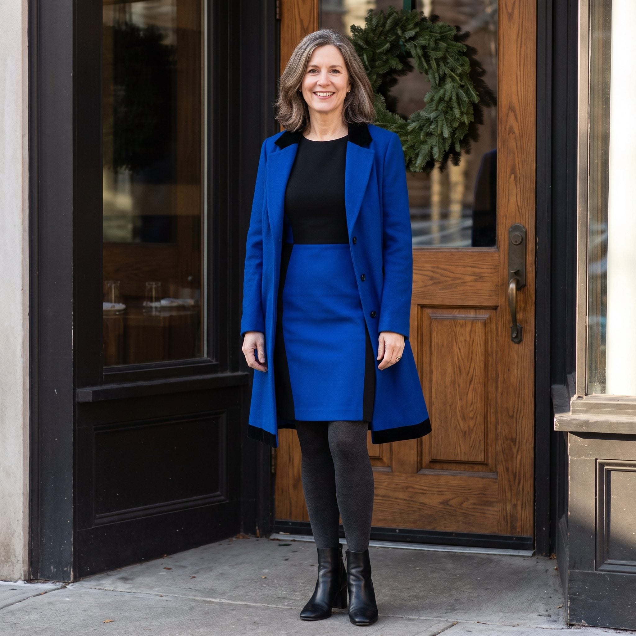 Cobalt wool coat with black velvet lapels over a two-tone black and blue sheath dress