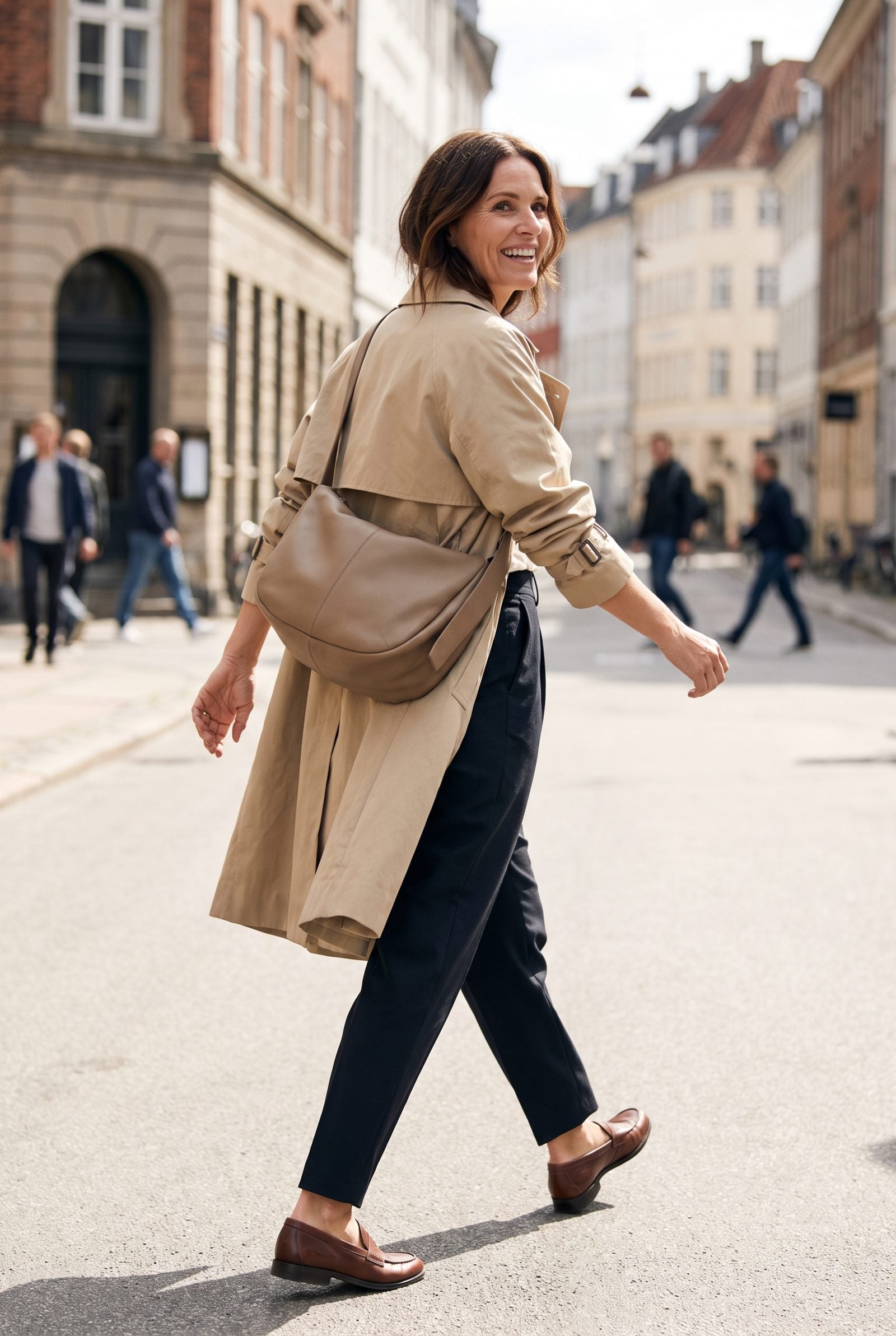 Woman at an outdoor market wearing a tan crossbody bag with the strap running diagonally across her body.