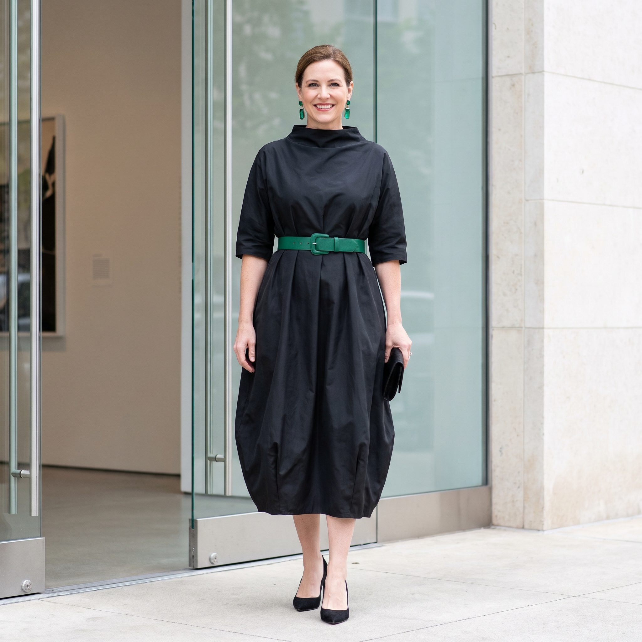 Black balloon-skirt taffeta dress with an emerald belt at the natural waist