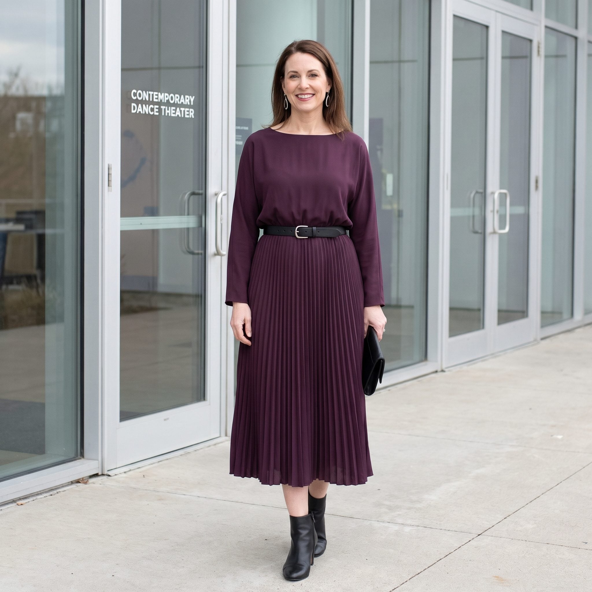 Plum pleated evening dress with a black belt positioned low on the hips