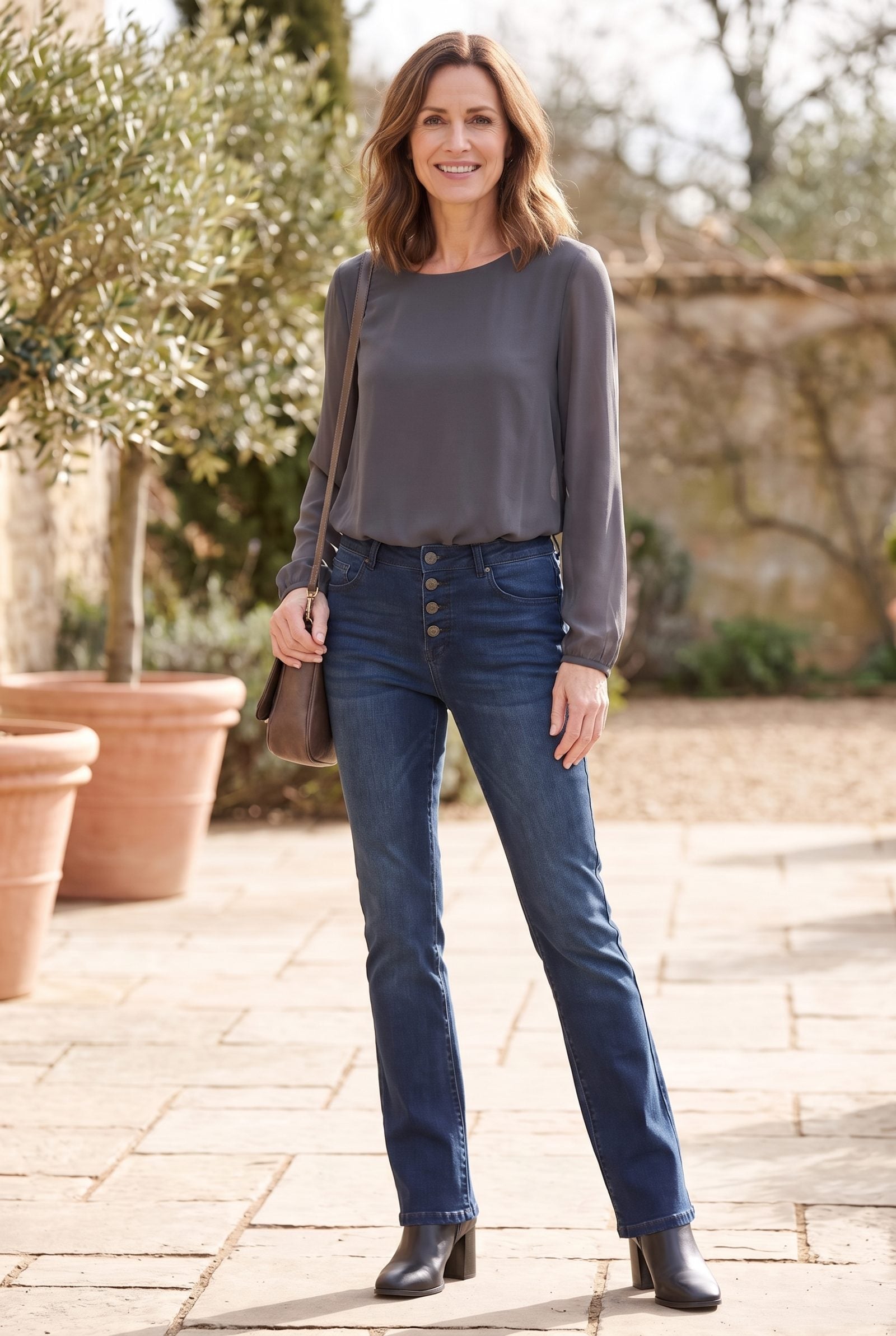 Woman in a cream double-layered blouse tucked into slim bootcut jeans, both layers bunching and thickening the waistband.