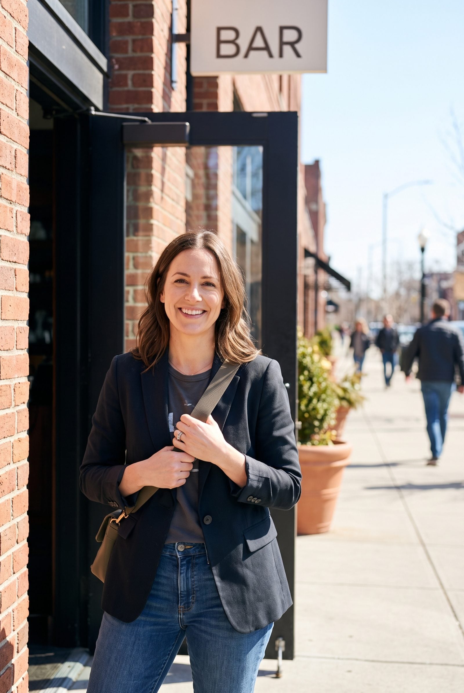 Woman on a sidewalk wearing a black leather crossbody bag with the strap running diagonally across her chest.